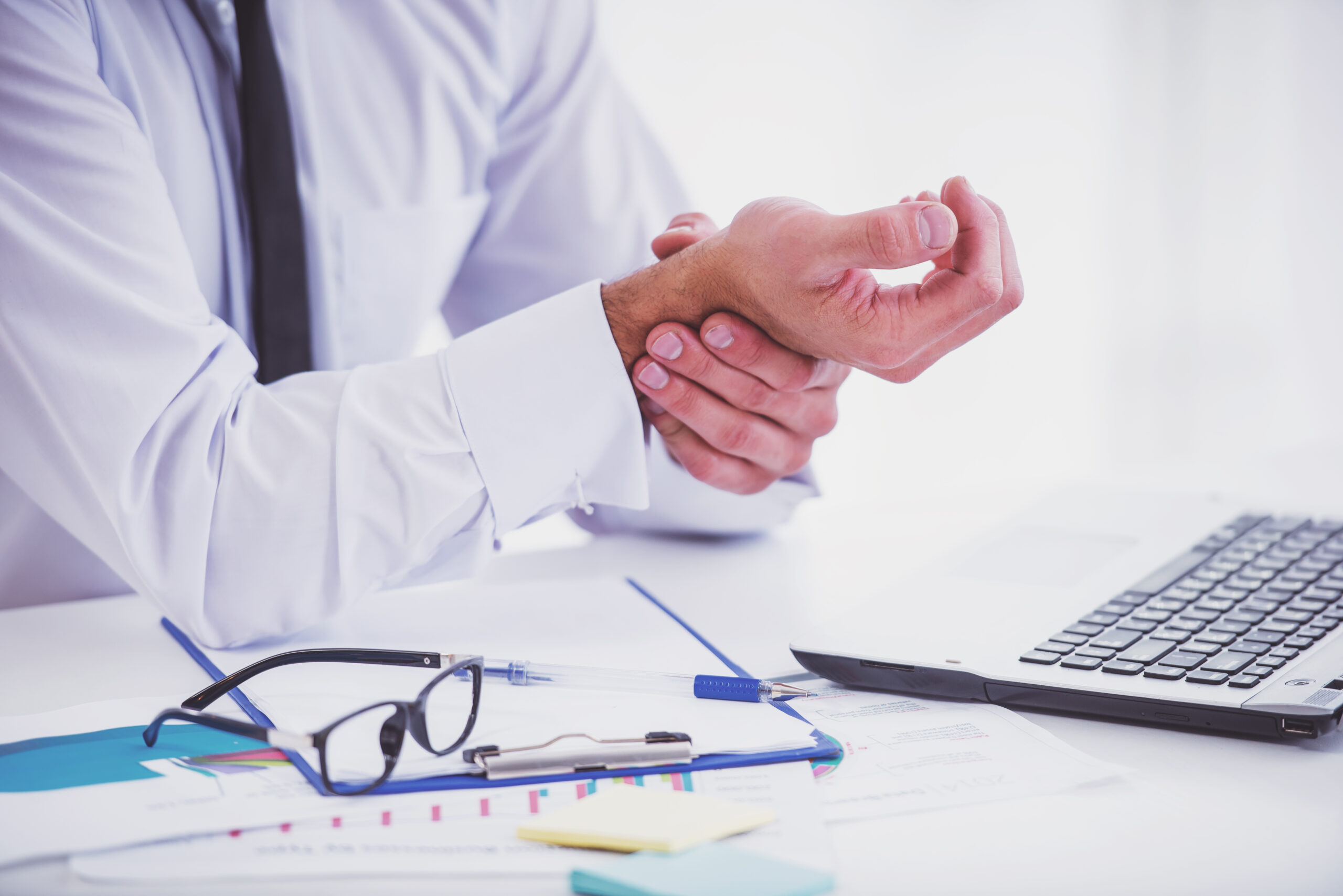 Illness hand. Portrait of a businessman with a beard while working in his office, holding hand